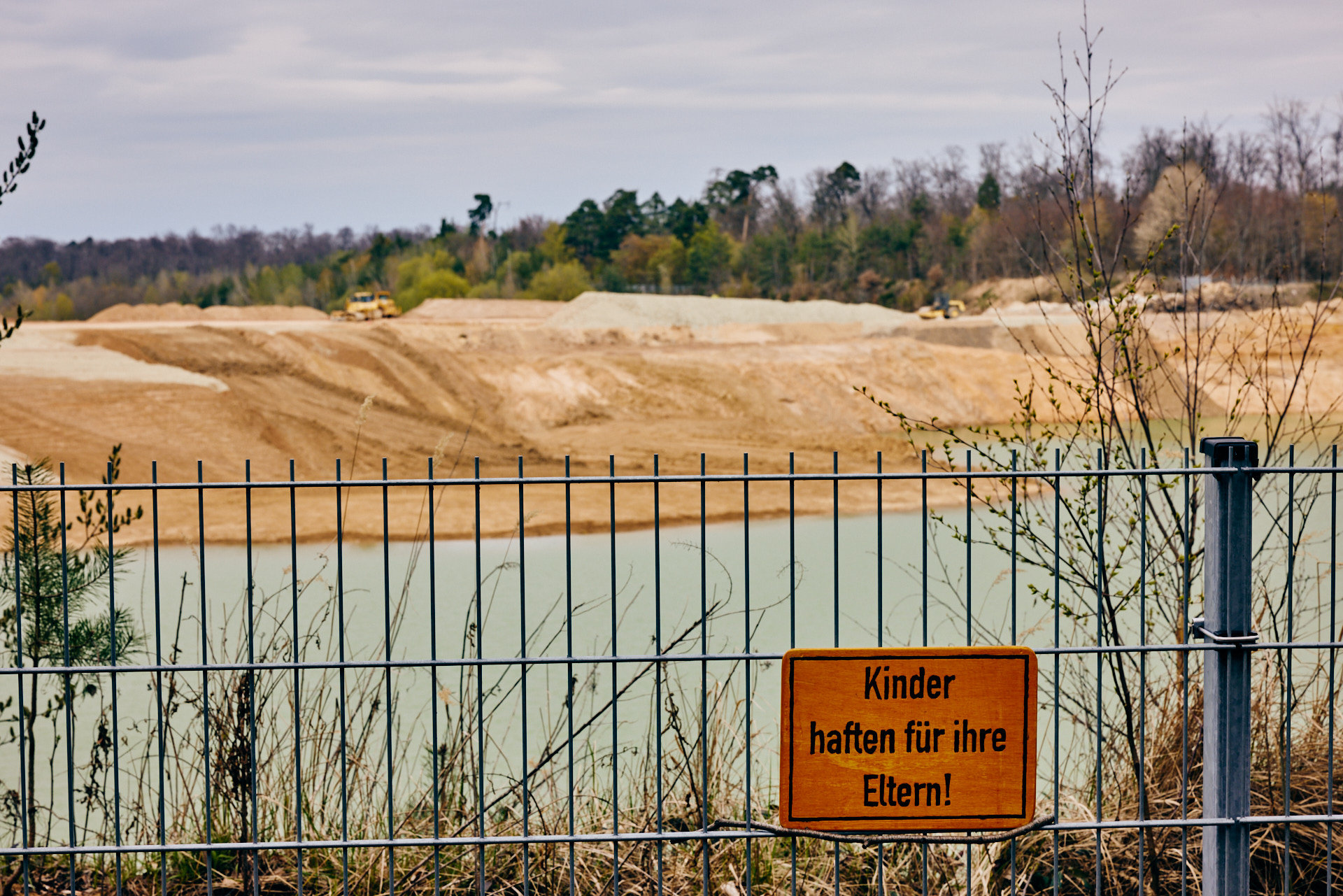 Endliche Bau-Rohstoffgewinnung: Sand- und Kiesabbau am Langener Waldsee mit Schild „Kinder haften für ihre Eltern!“ (Foto: Niko Martin)