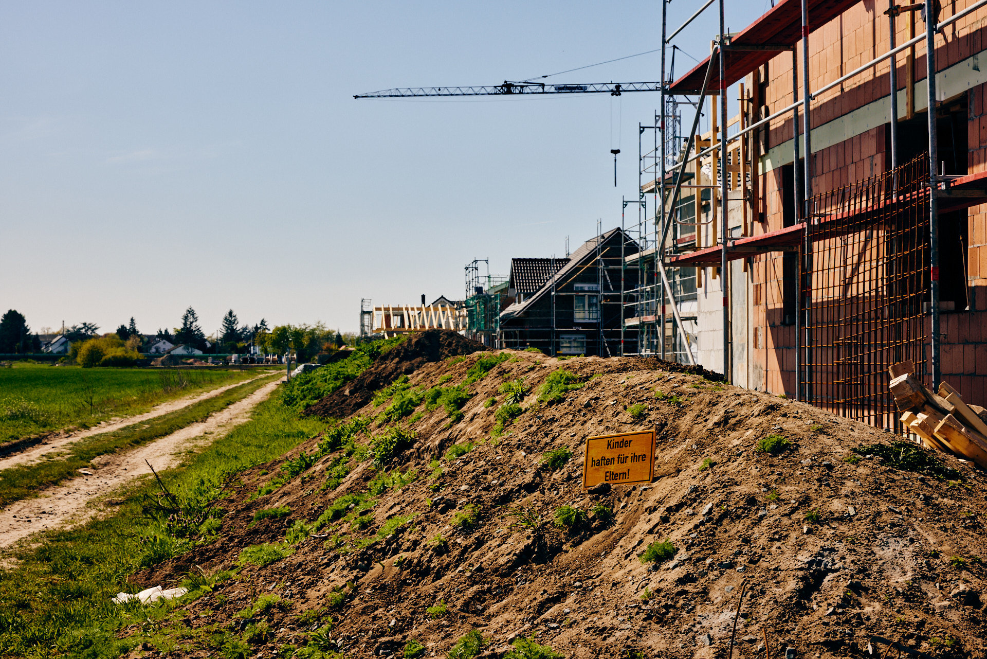 Ein Neubaugebiet auf ehemaligen landwirtschaftlichen Flächen in Südhessen mit Schild „Kinder haften für ihre Eltern!“ (Foto: Niko Martin)